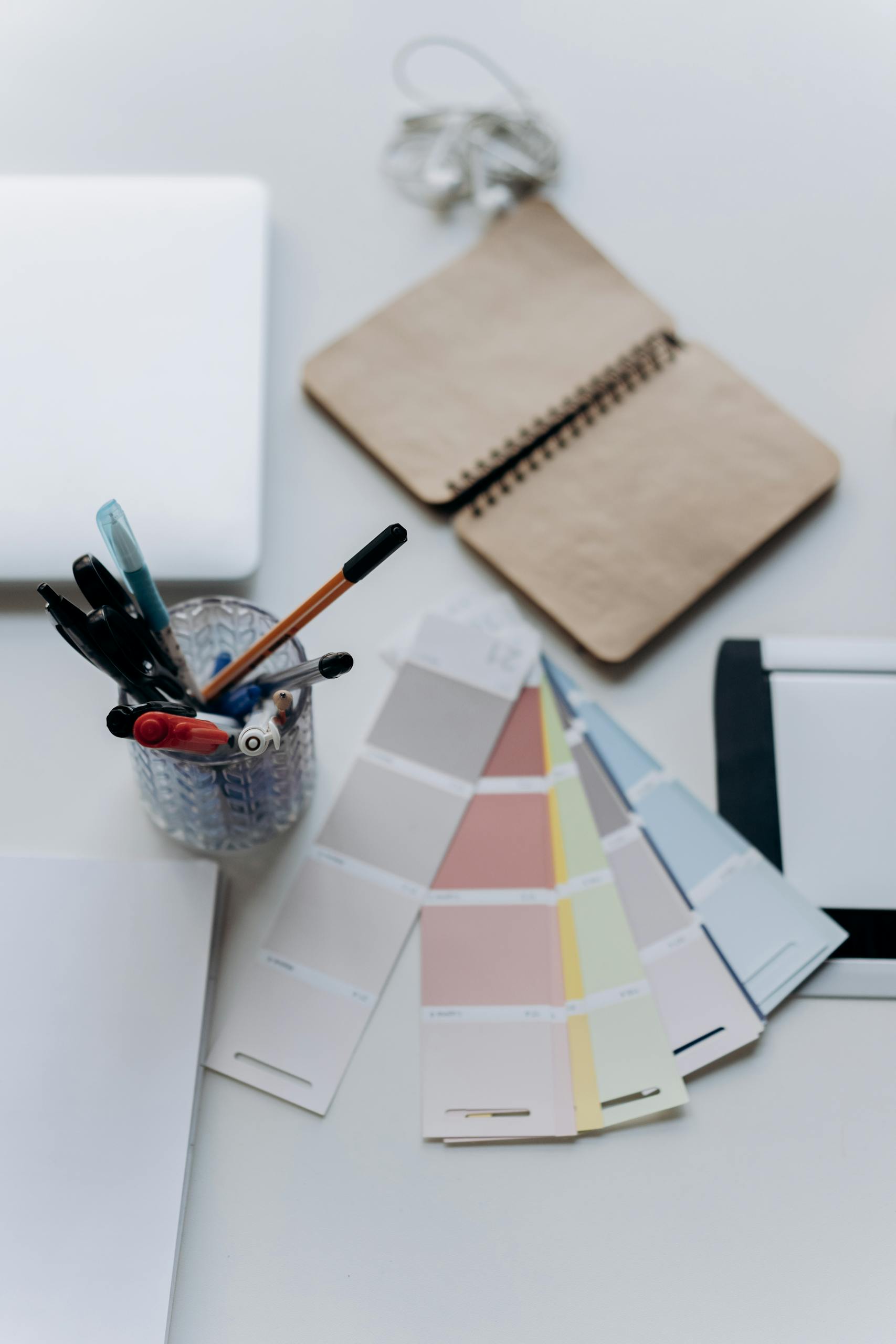 Organized workspace featuring color swatches, notebook, laptop, and stationery for design projects.